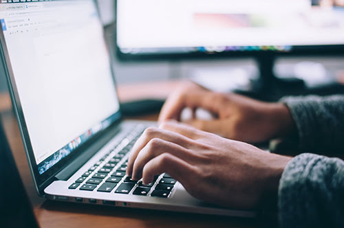 Person writing email campaign to market silent auction on laptop